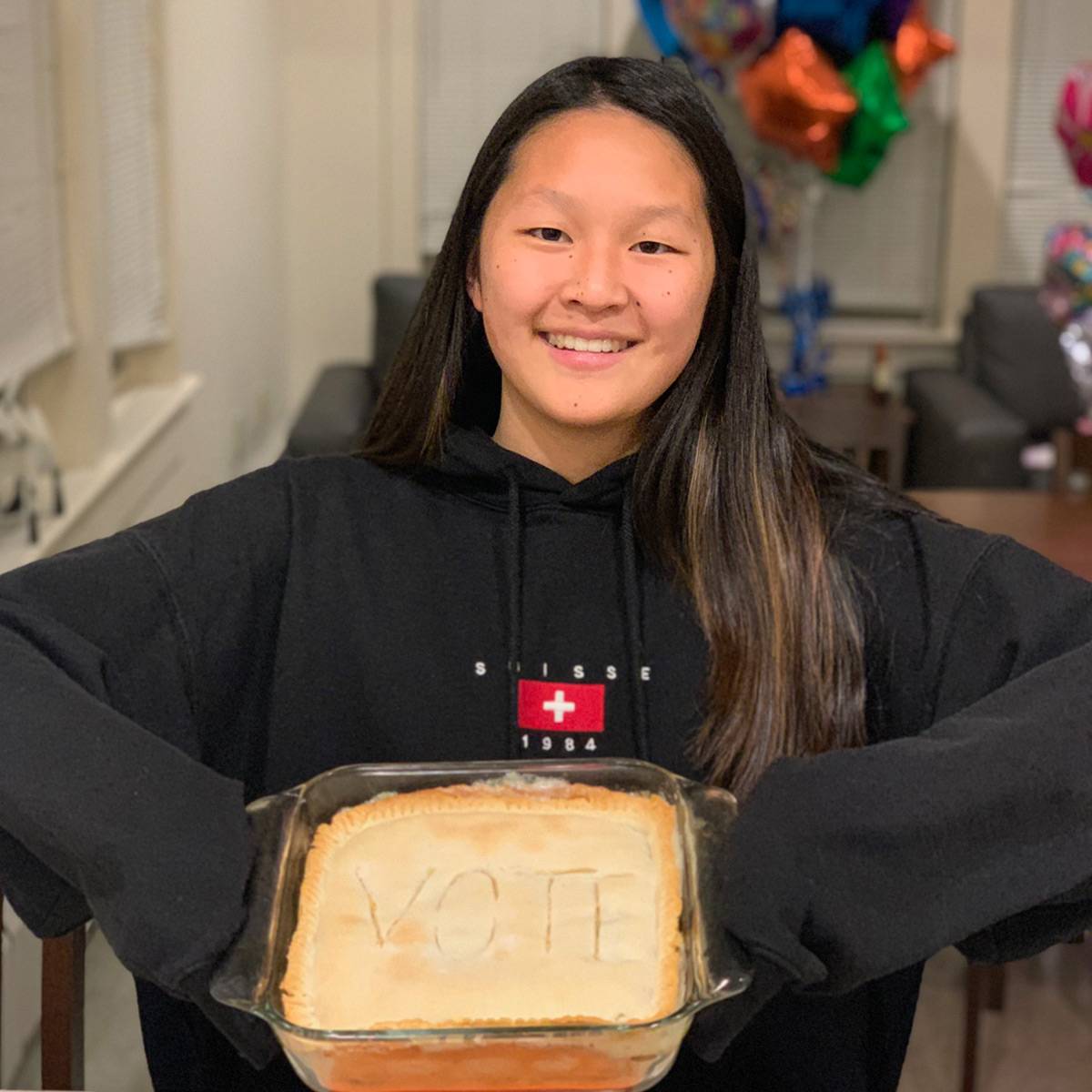 Eliza holding a cake that says vote.