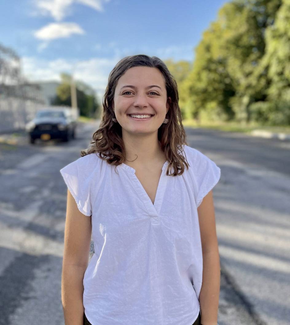Photo of Kelsey Bennett wearing a white shirt with a blue sky in the background.