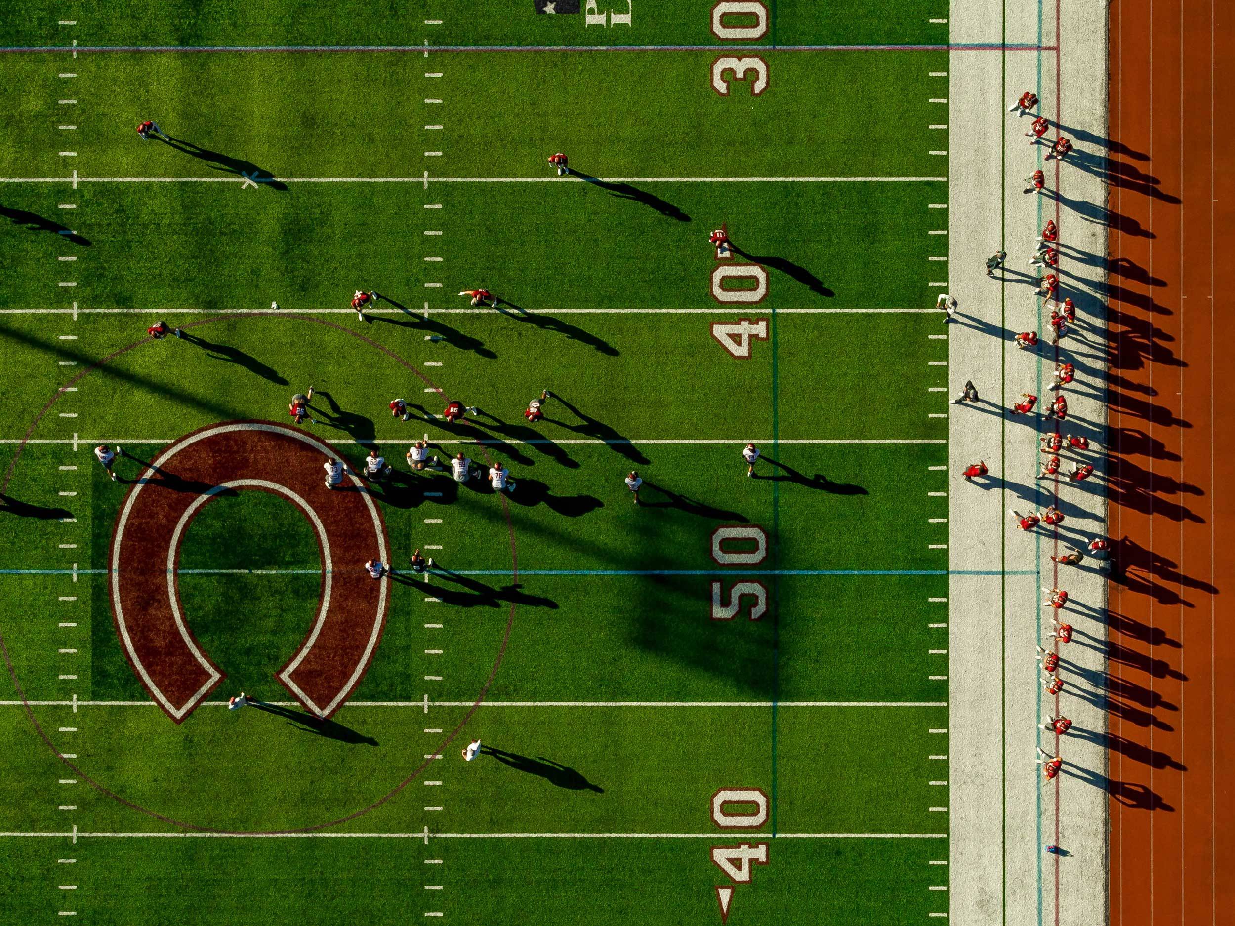 The Colgate Raiders football team practices in the late afternoon sun.