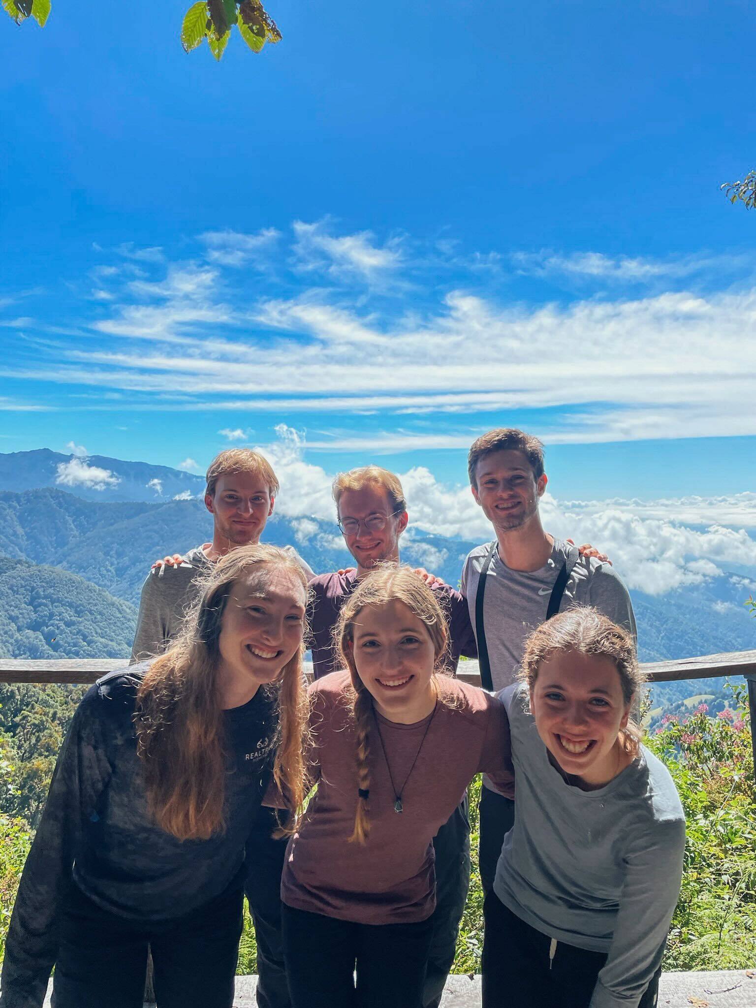 A photo of six students standing in front of a mountainous viewpoint.