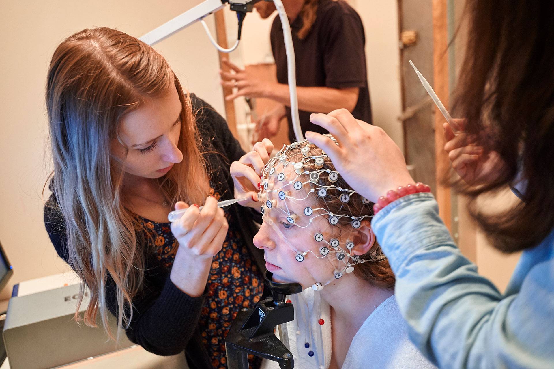 Students place a brain sensor cap on another student