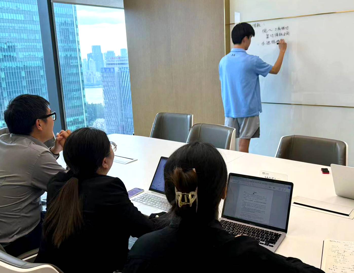 Young Hu ’27 writes on a whiteboard while mentors watch