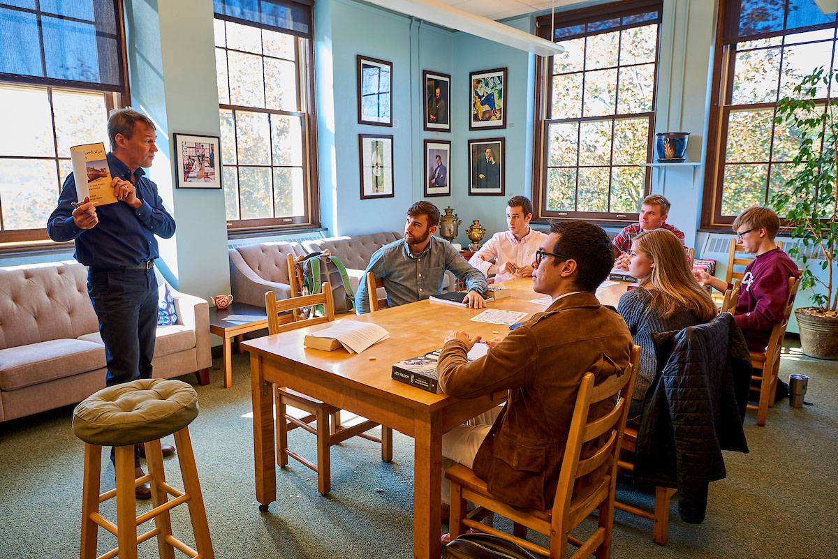 A group of students around a table while professor teaches