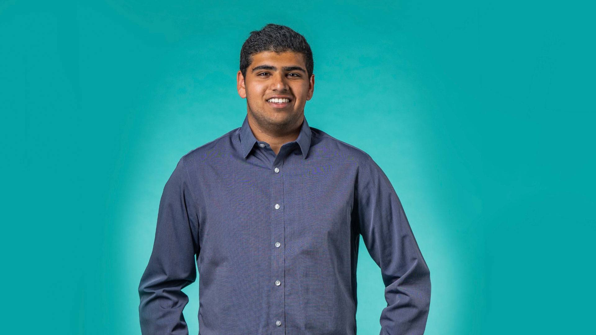 Nikhil standing in front of a green background.