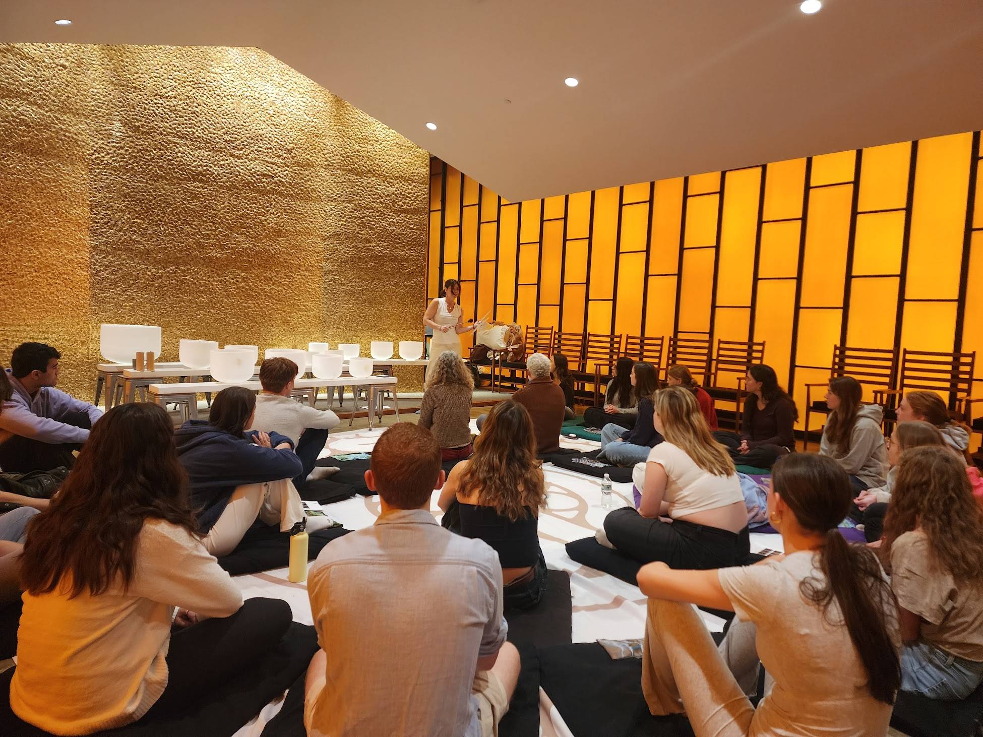 People seated on the floor during sound meditation led by instructor