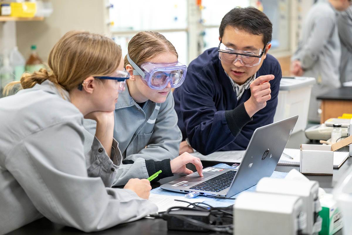 A professor explains research process to two chemistry students