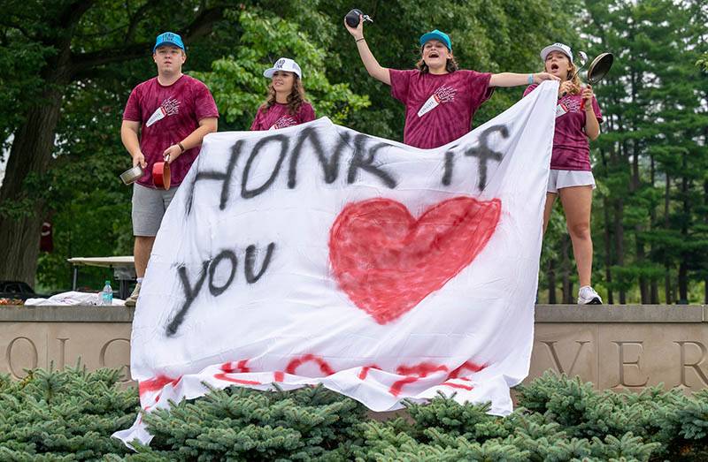 Students hold a sign that says honk if you love Colgate