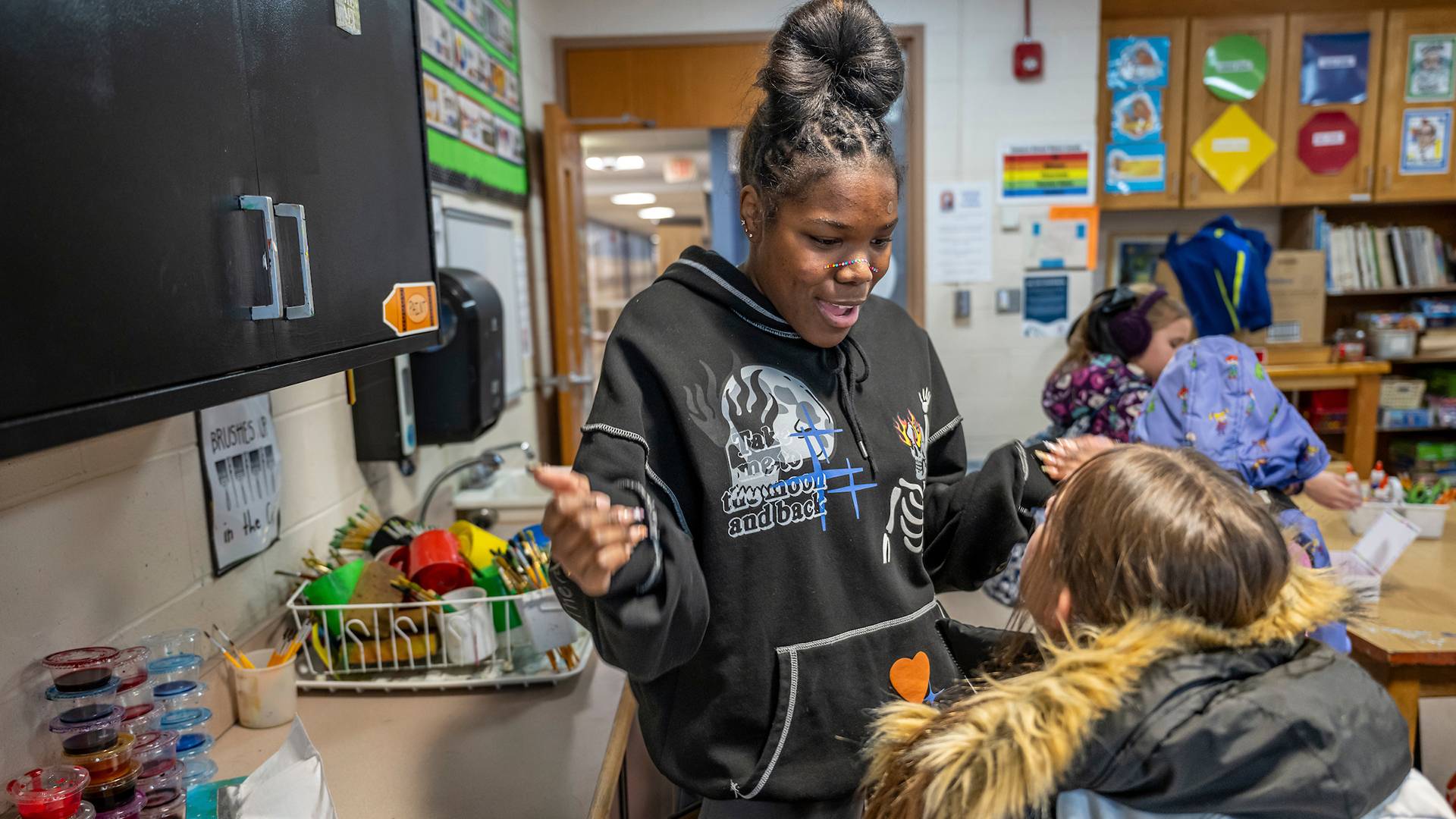 A college student visits with an elementary student in a classroom.
