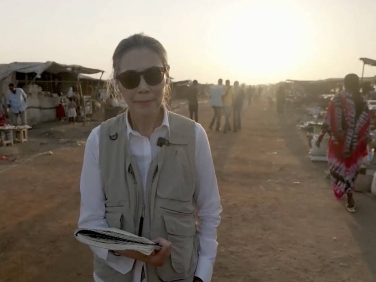 Journalist Ann Curry wears sunglasses on a dirt road at sunset 