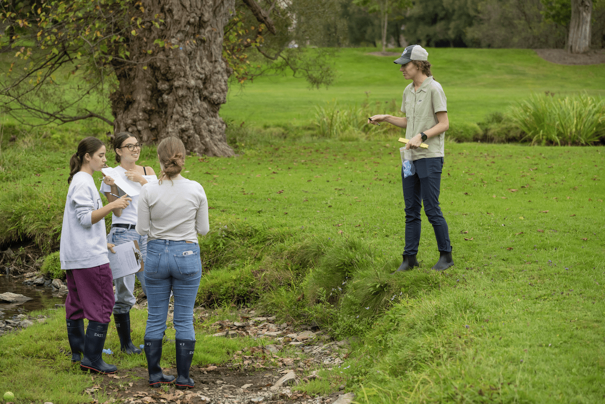 Emily Ury instructing students during a lab. She stands on a stream bank.