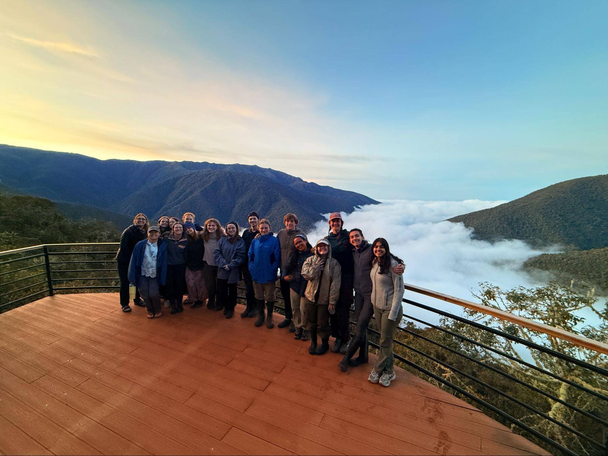 Students pose for a picture under a vibrant sunset descending upon the Peruvian rainforest.
