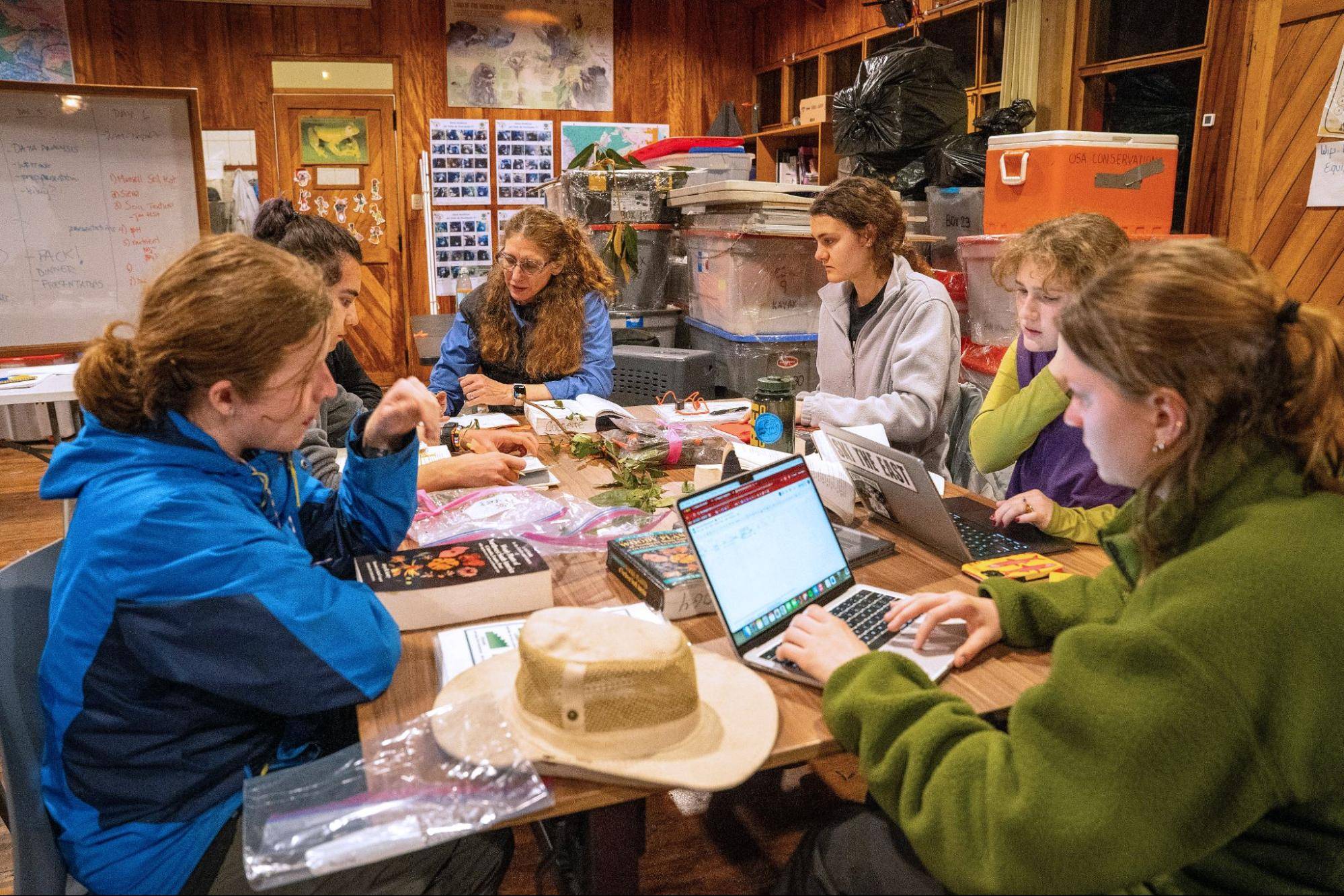Students gather around a table to review and document ecological data.