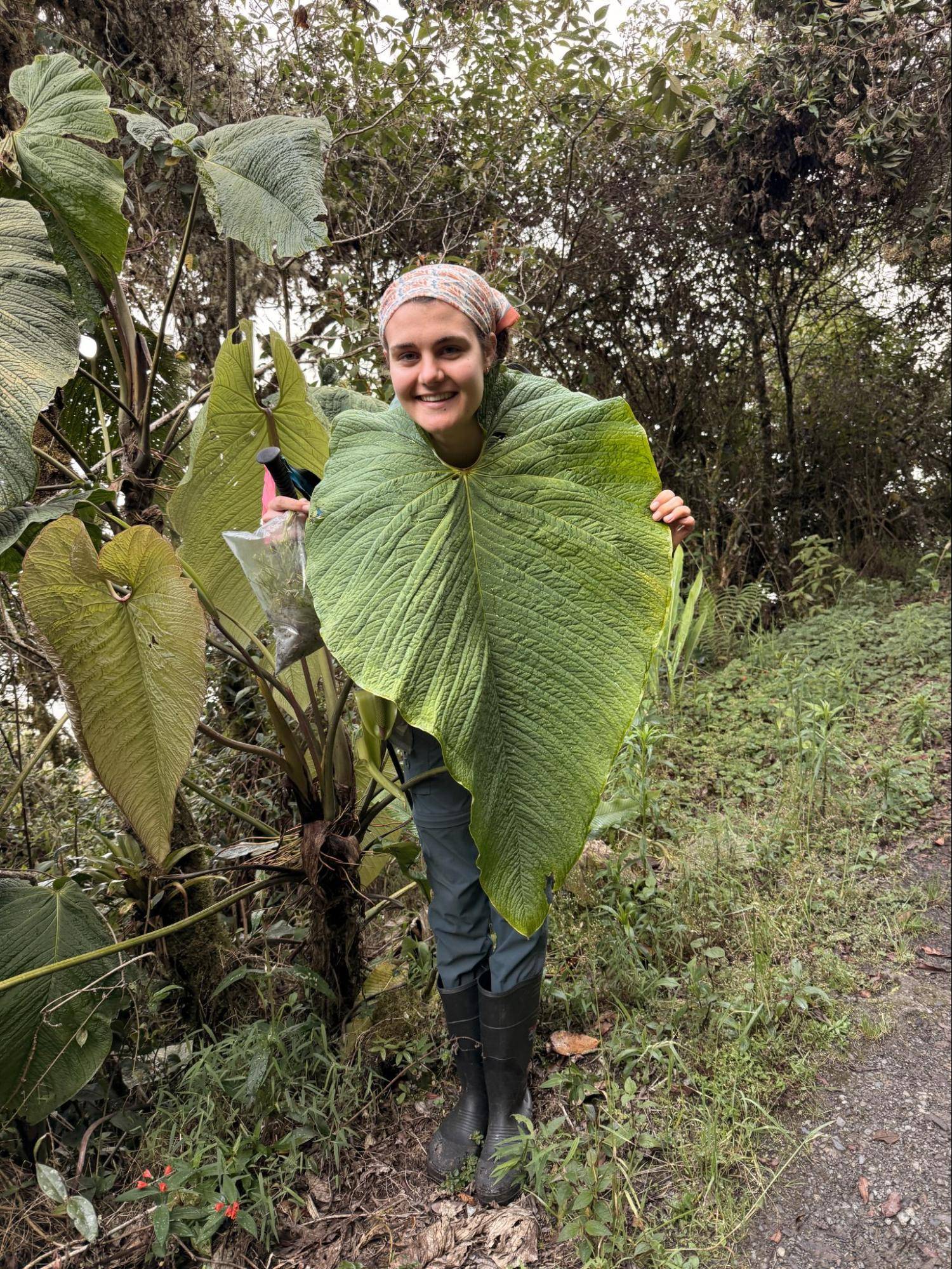 Student poses with a large tropical leaf.