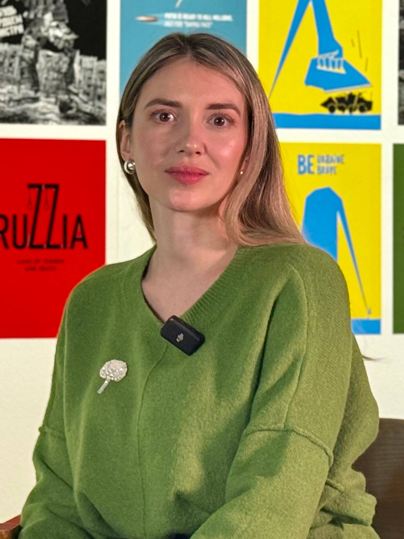 Olena Speranska poses in front of Ukrainian War Posters displayed in the Clifford Gallery.