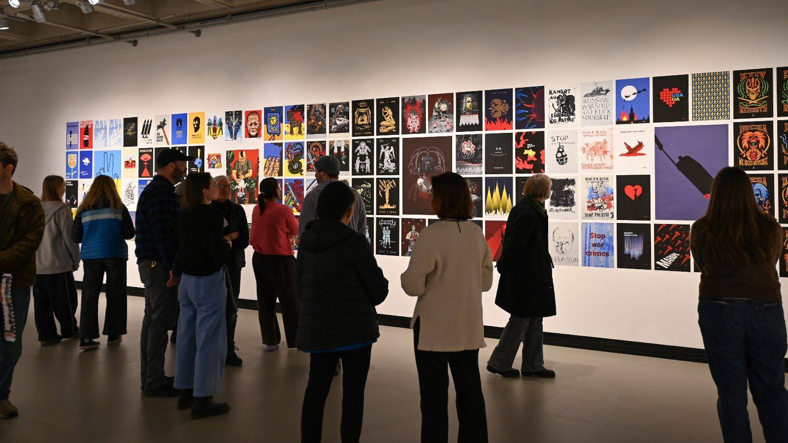Visitors view more than 300 graphic works on display at a new Clifford Art Gallery exhibition “Ukraine Wartime Posters, 2022–2025: The Way of Resistance” during the opening Feb. 25. 
