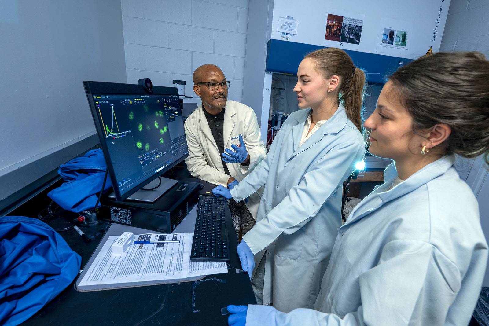 Two students work with a professor in the lab