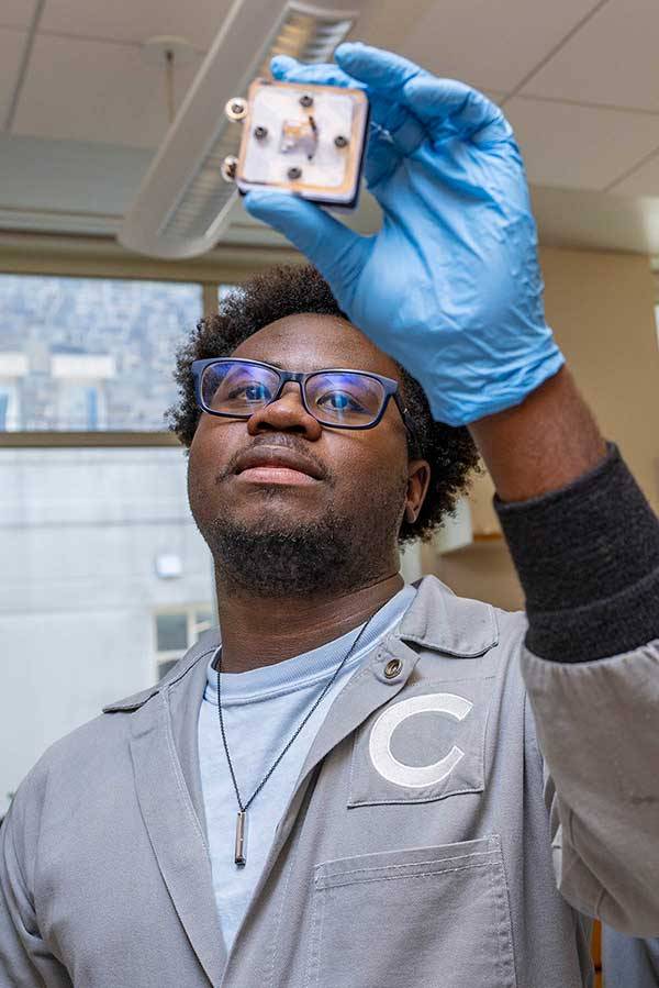 Student holds up a leaf powered battery