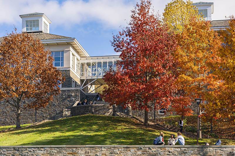 Students sit on the stone wall outside of Persson Hall
