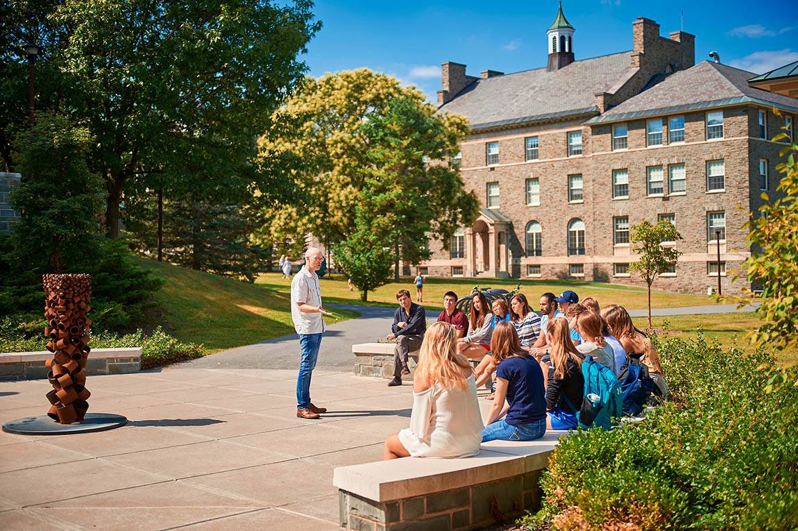 Students sitting on a bench listening to a professor