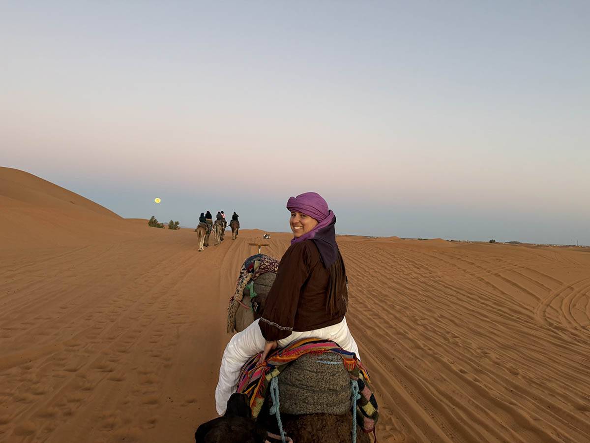 Alisha Greenstein rides a camel in the desert