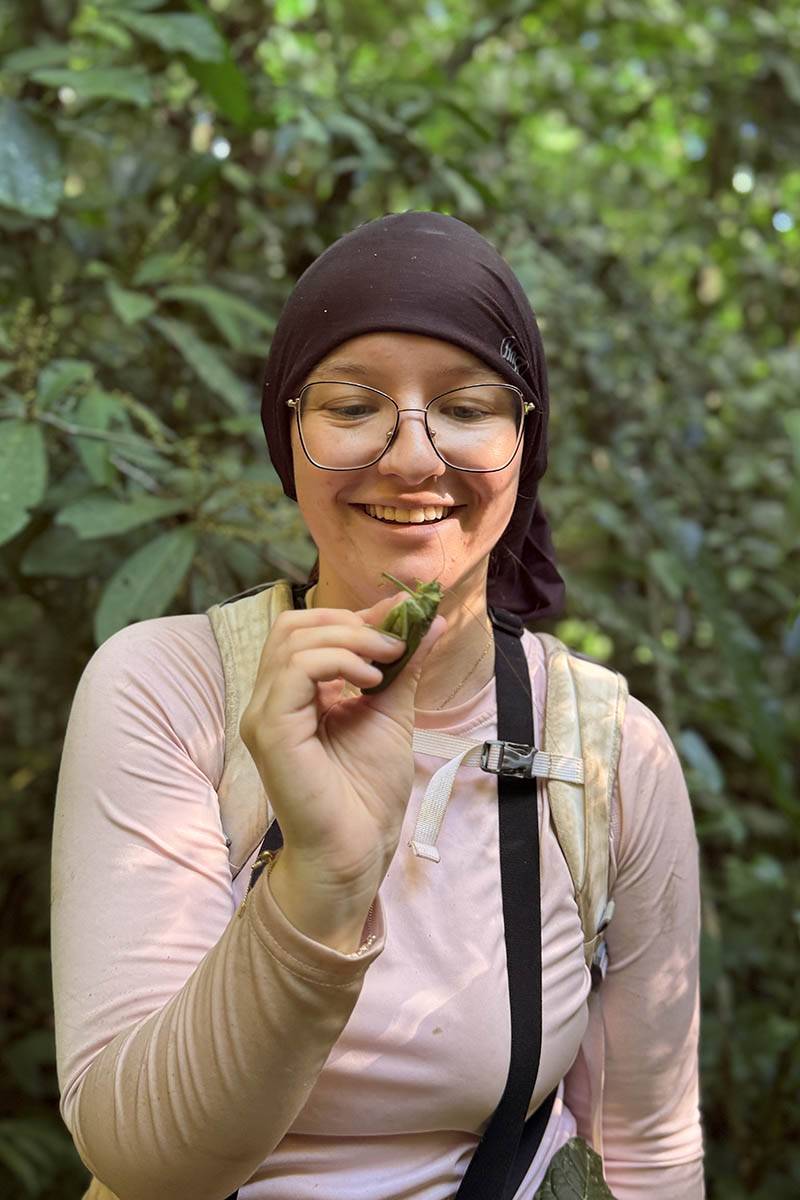 A student looks at the plant in her hand