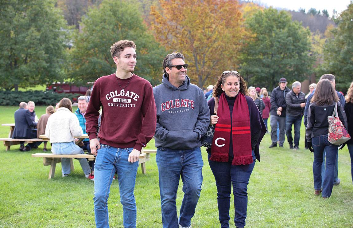 Two parents and their student walk on the lawn