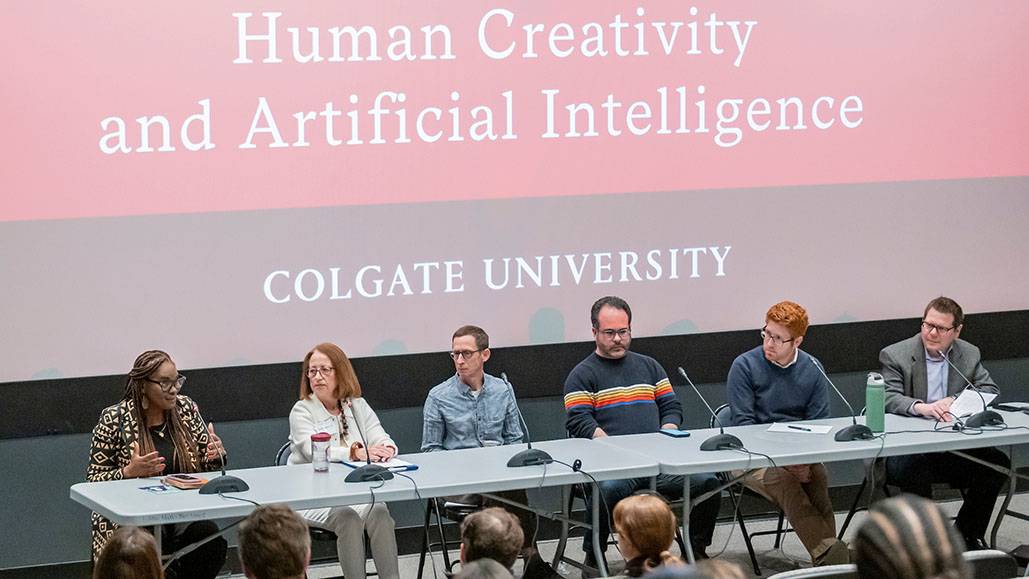 Panelists sit on a stage with microphones