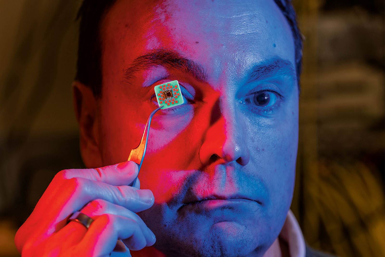 Ken Segall holds a microchip to his eye