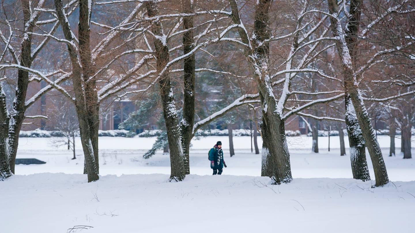 Student walking on campus during a snowy winter.