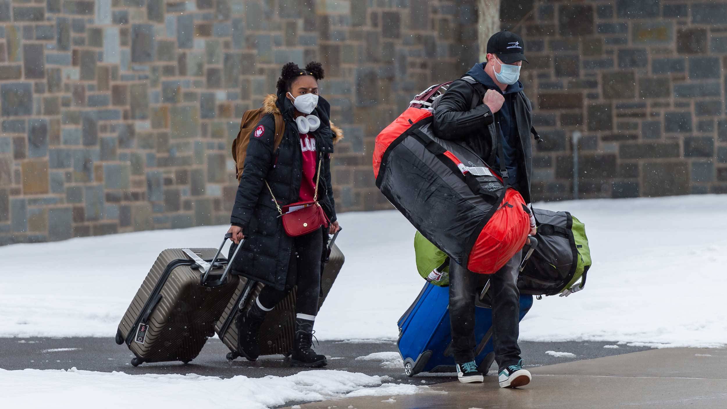 Students carry luggage through stnow