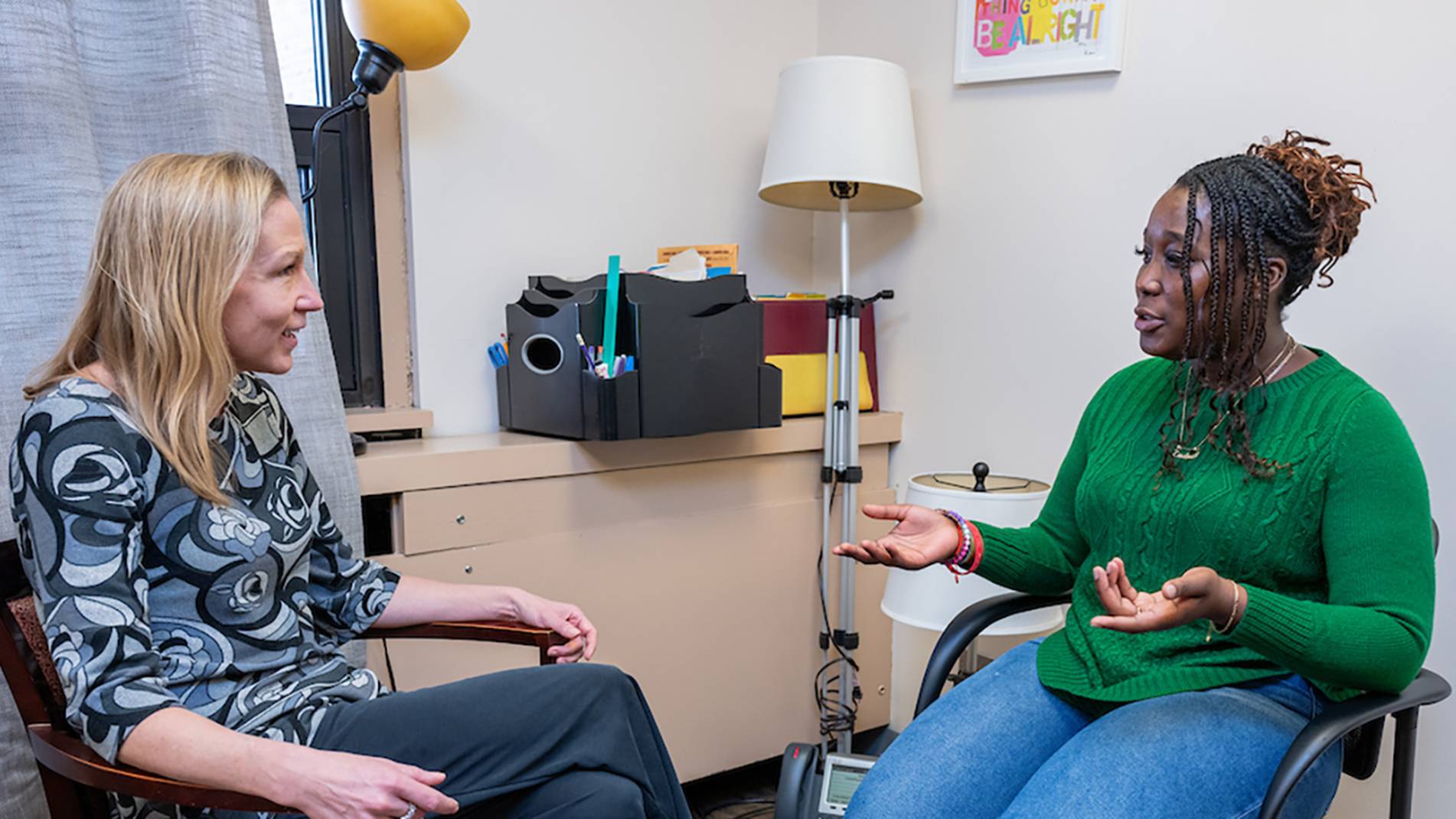 A mental health professional and a student visit in an office space.