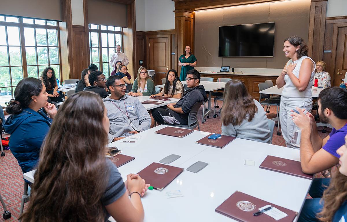 Teresa Olsen talking with a group of students at tables in Benton Hall