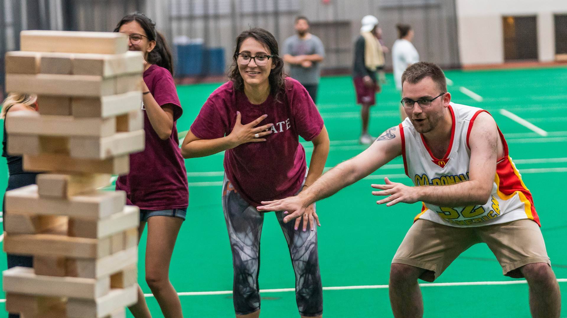 Colgate staff members cheer each other on in a game of giant Jenga