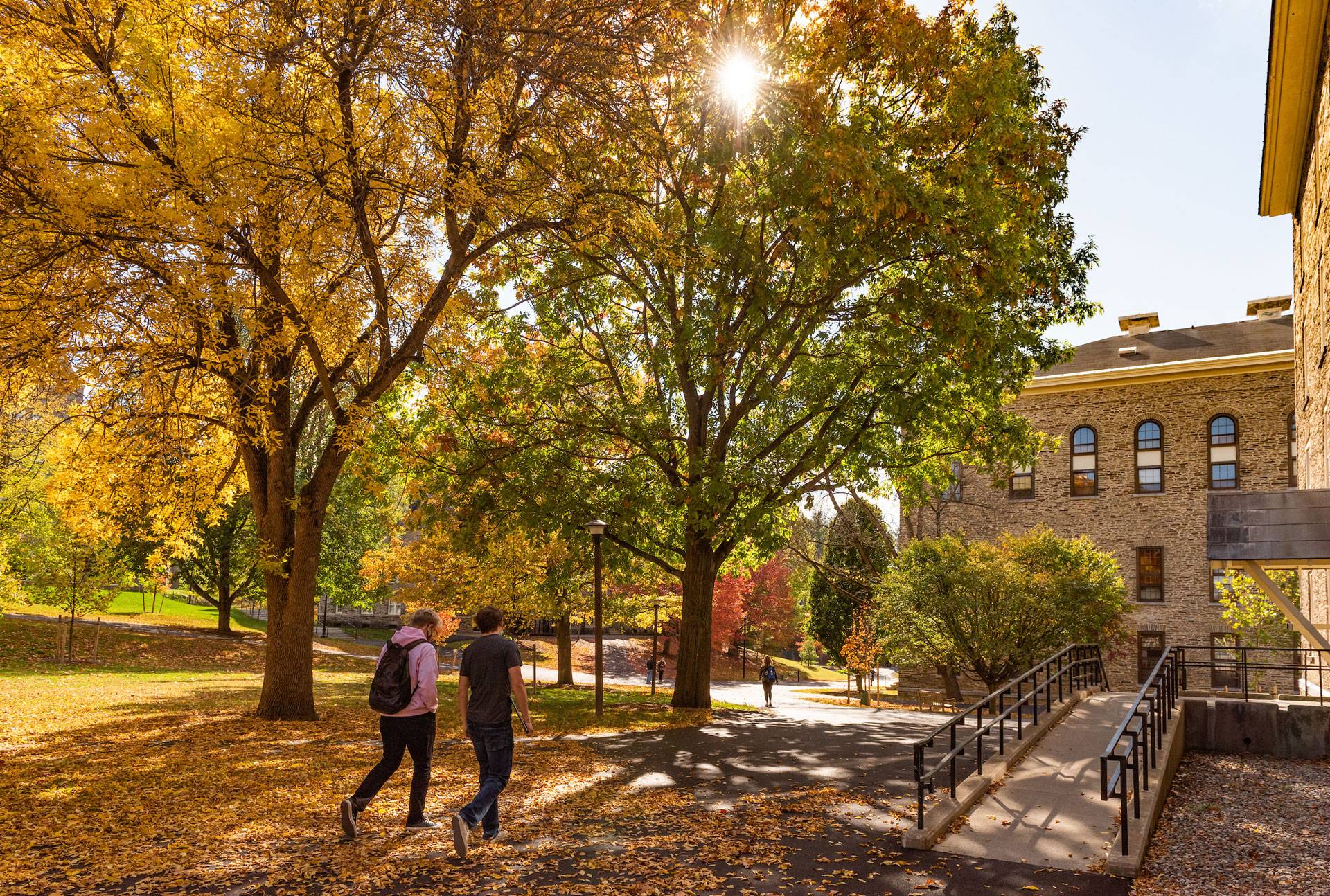 Students walking toward Alumni Hall on the Residential Quad, an accessiblity ramp to their right.