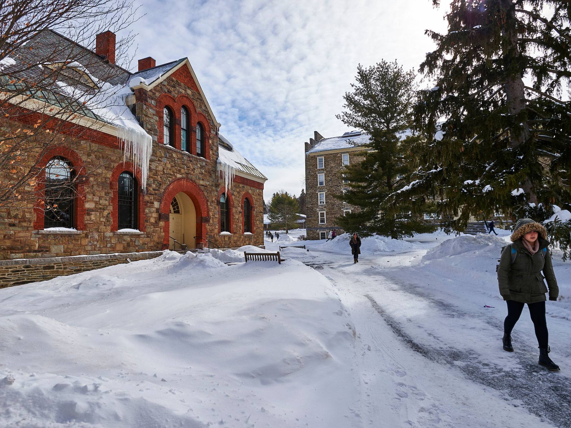 Student walking past Hascall Hall in snow