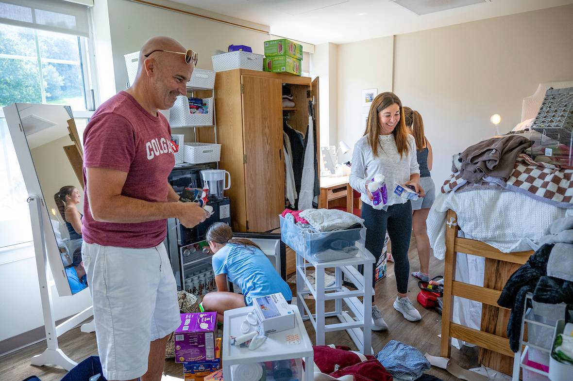Man and woman help student move into dorm room
