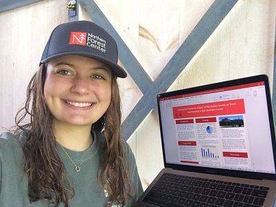 Kelsey Bennett sitting next to her computer with a presentation made for the Northern Forest Center