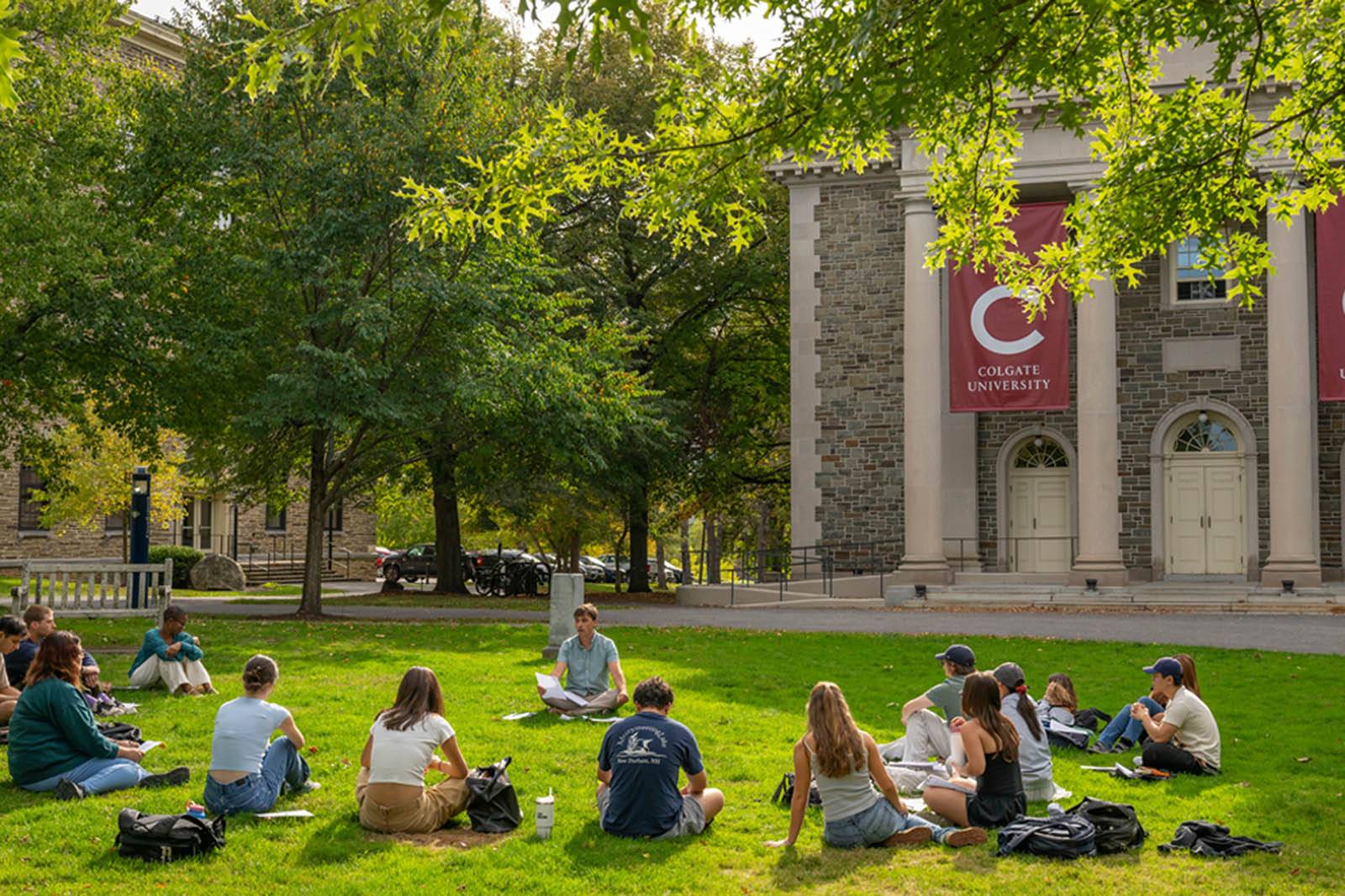 A professor and their class sitting in the grass outside of the Memorial Chapel