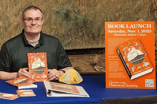 Image of Christian Vischi seated at a table holding up his new book