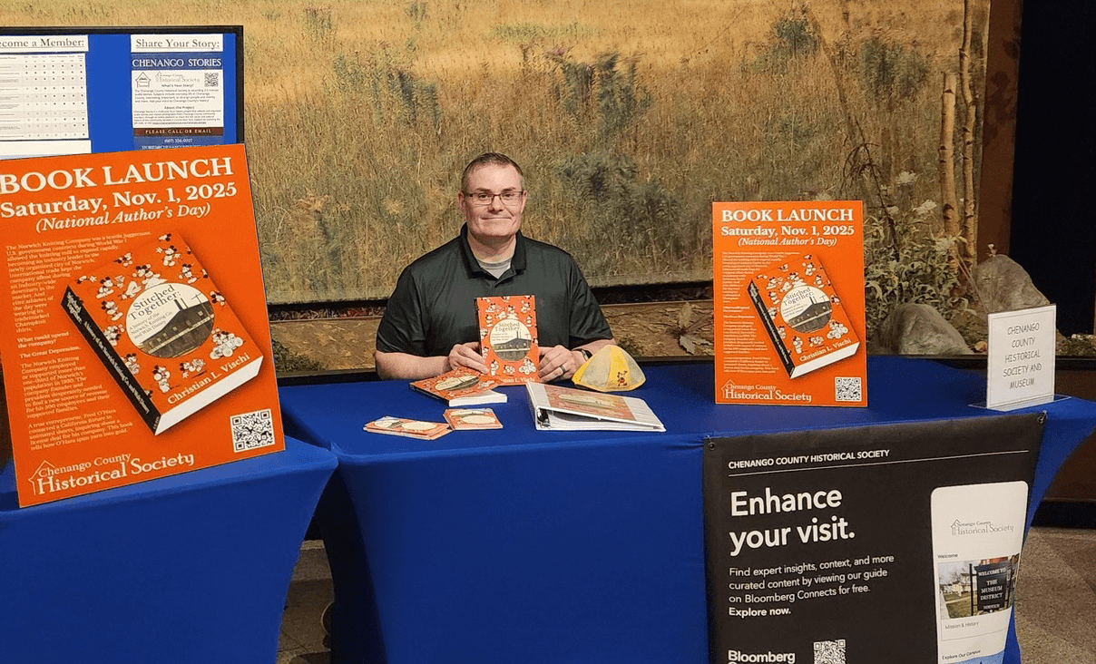 Image of Christian Vischi seated at a table holding up his new book