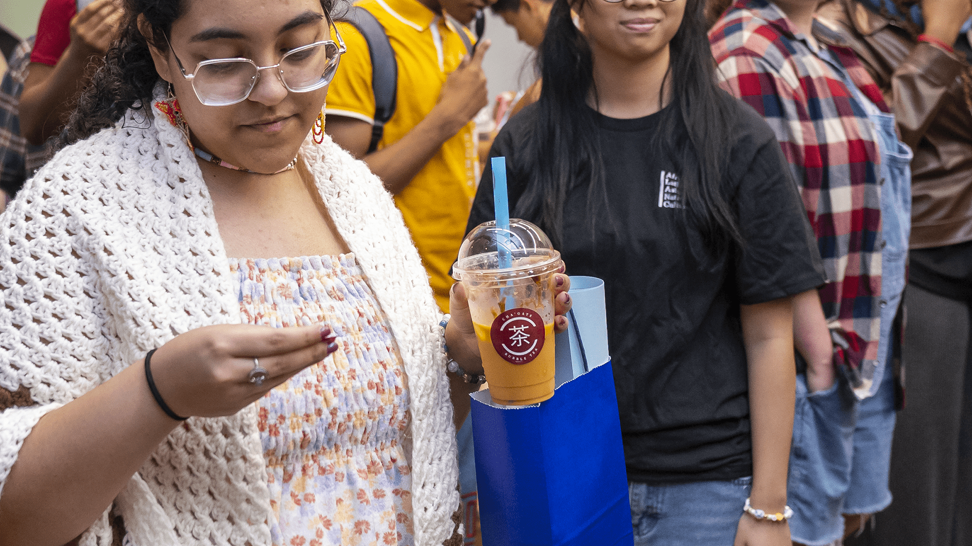 An attendee to ALANAPalooza holds a cup and straw with a Cha'Gate sticker on it.