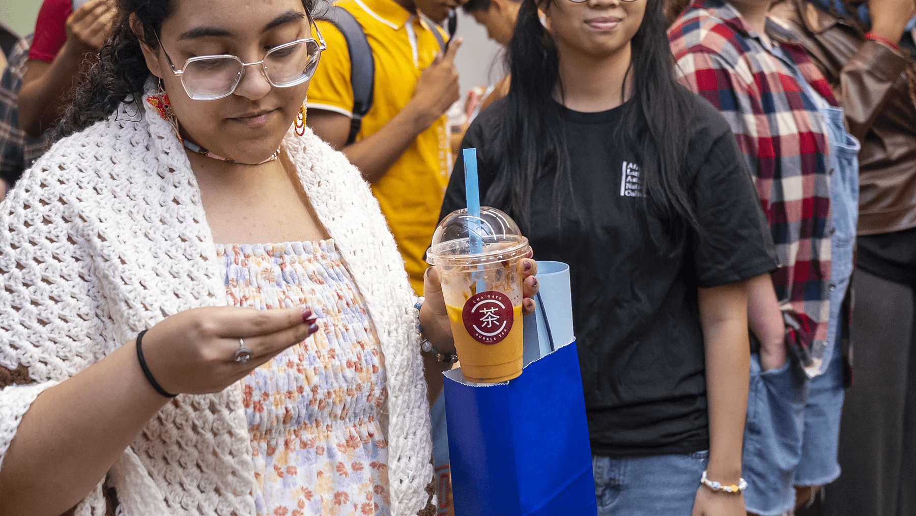 An attendee to ALANAPalooza holds a cup and straw with a Cha'Gate sticker on it.