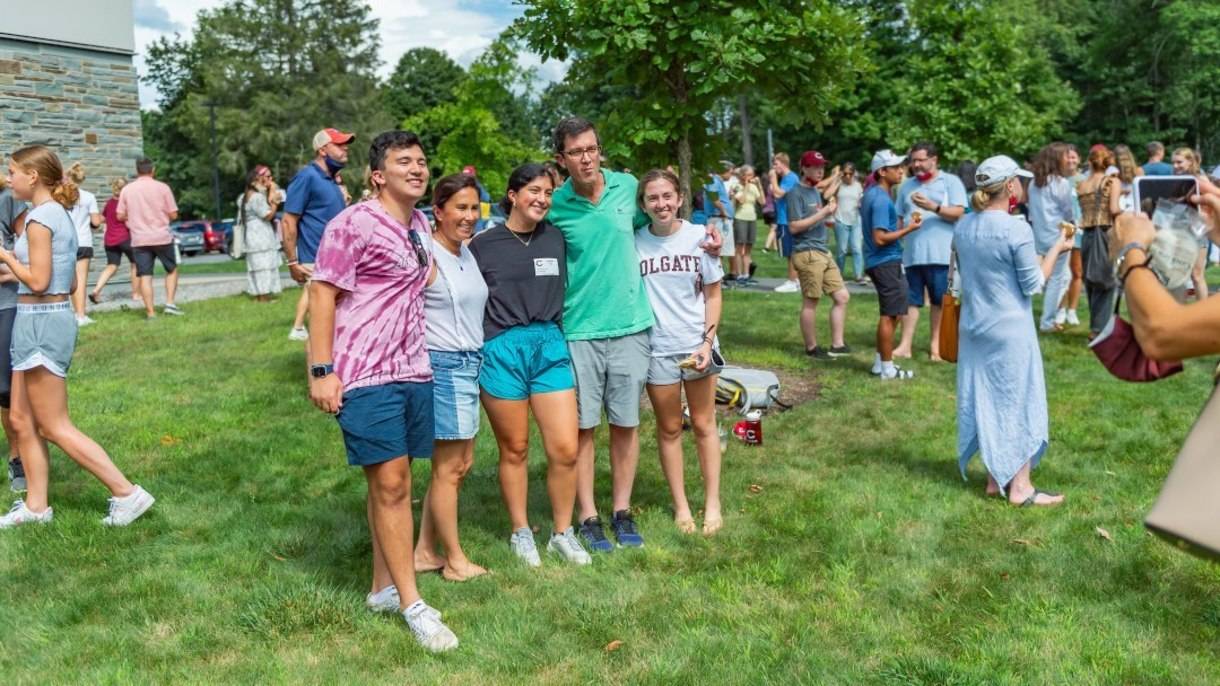 Family has their photo taken on Colgate campus as others gather outside during move-in weekend.