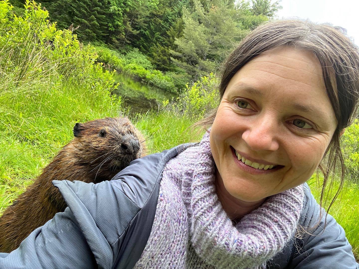 Photograph of artist Suzanne Husky with a beaver peeking over her shoulder