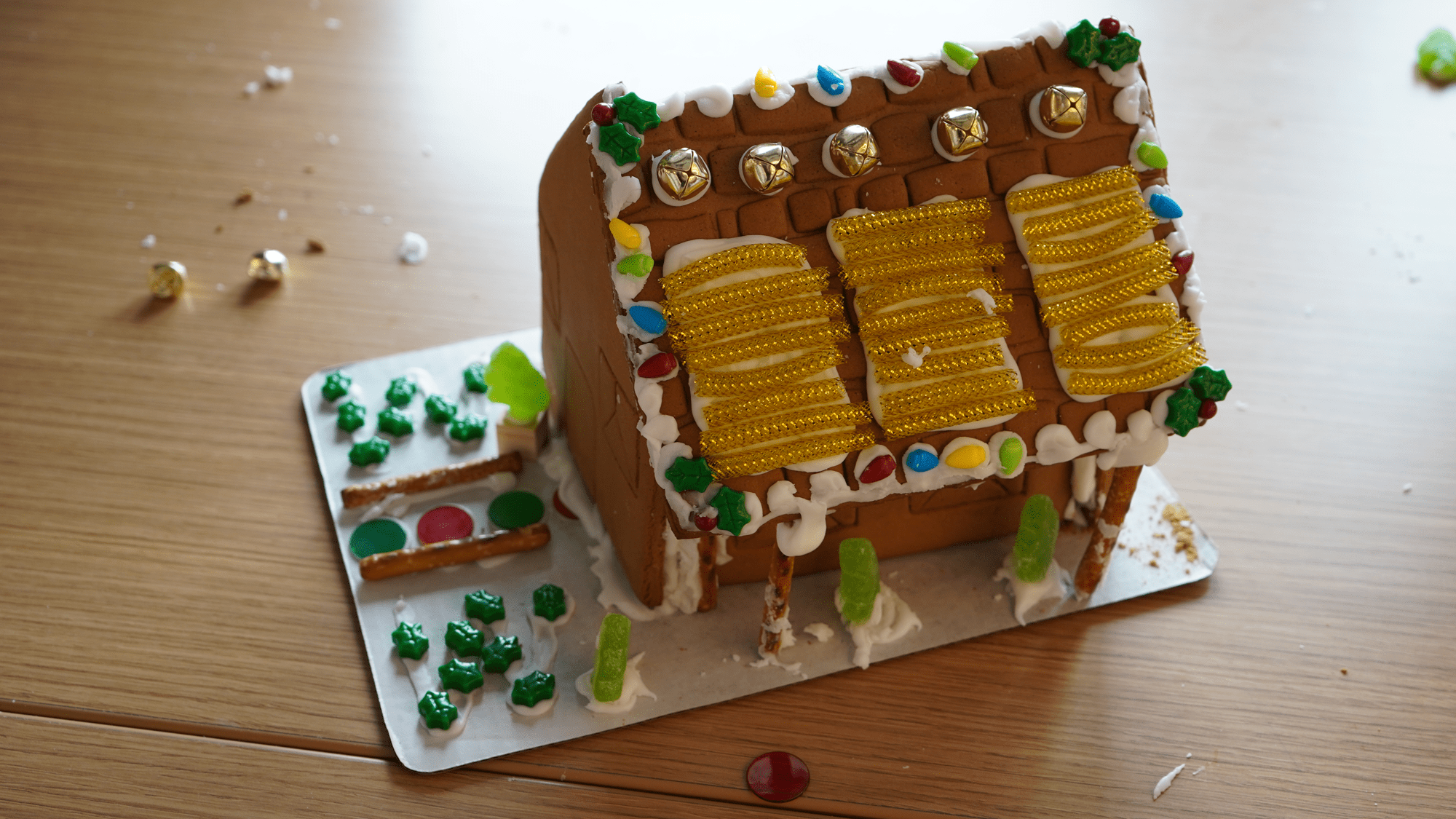 A picture of a gingerbread structure, featuring icing and paracord solar panels on the top and a small front yard of icing and candy.