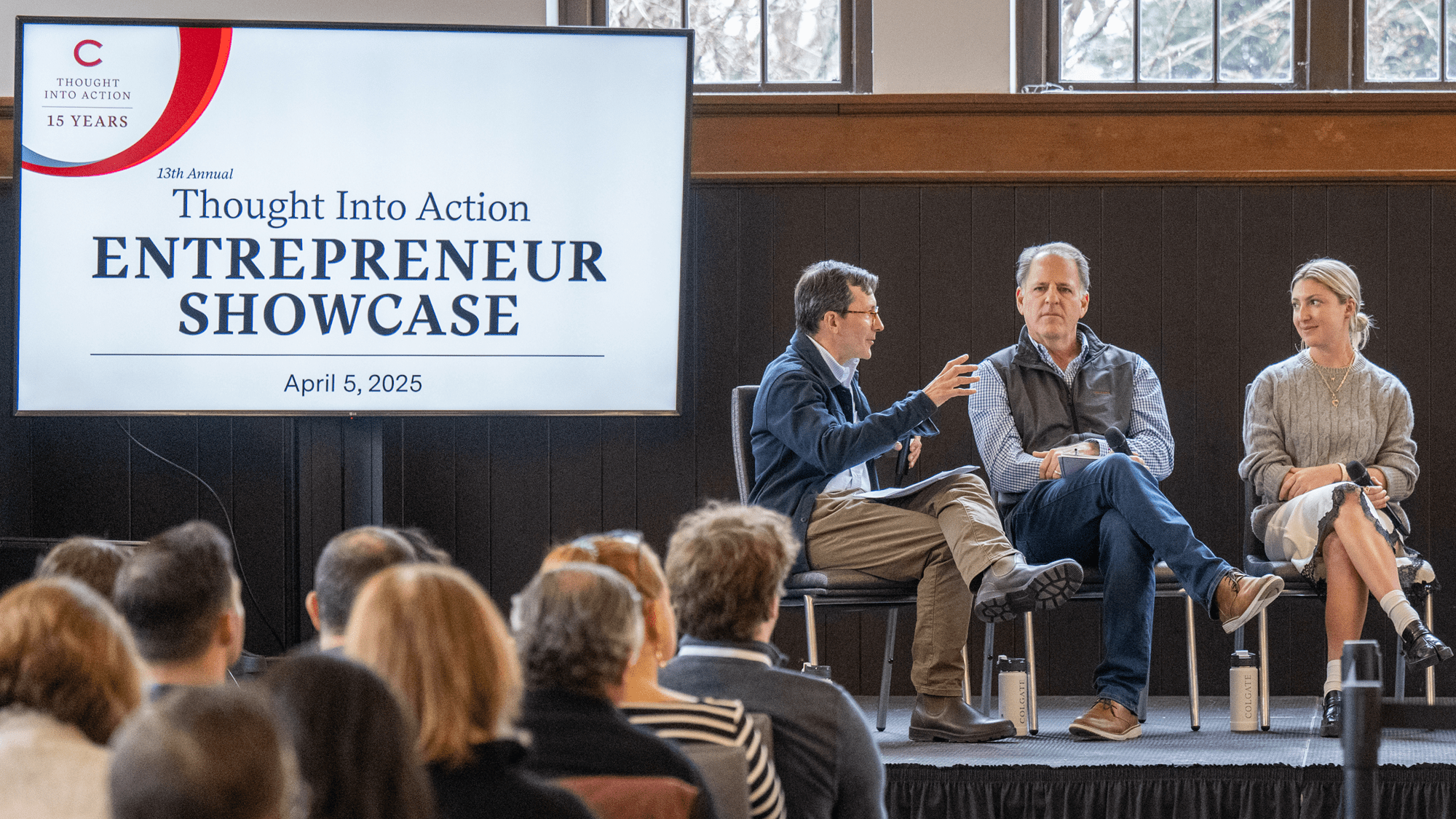 Gus seated on stage, speaking to two other people also seated.