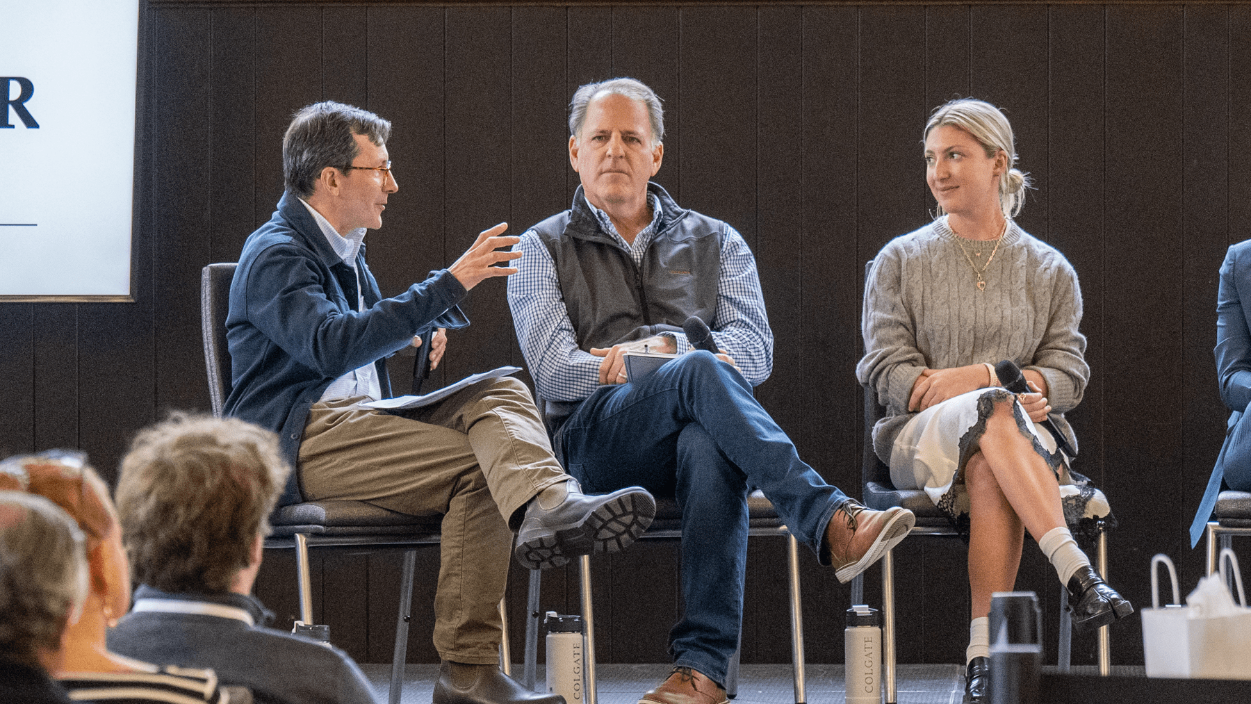 Gus seated on stage, speaking to two other people also seated.