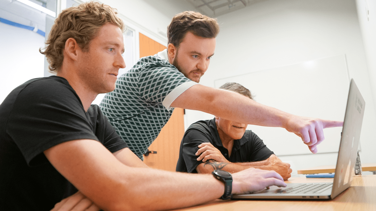 Hunter Macy '22 seated looking at a computer screen with Entrepreneur in Residence Reece Wilson standing behind him and pointing at the screen.