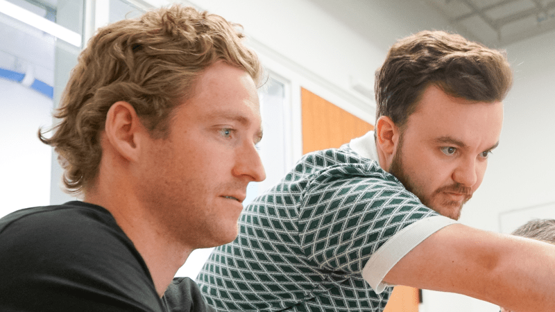 Hunter Macy '22 seated looking at a computer screen with Entrepreneur in Residence Reece Wilson standing behind him and pointing at the screen.