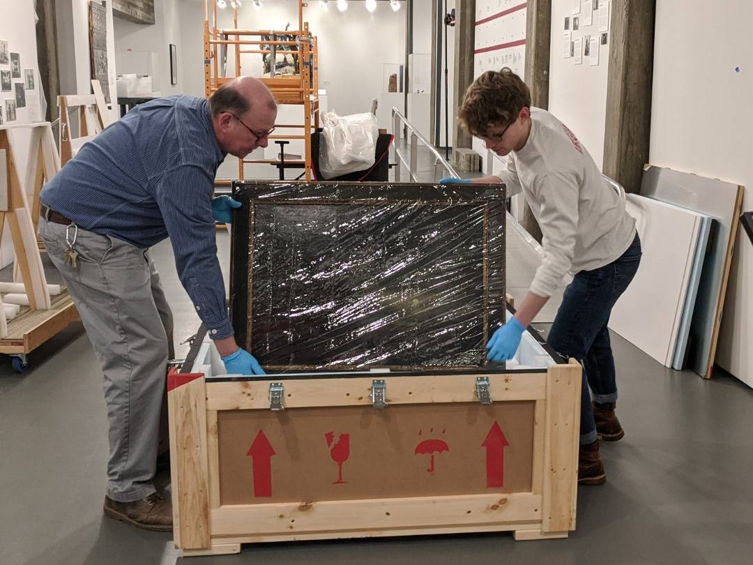 Preparator Scott Lewis and student assistant Daniel Shea ’20 unpack objects from a crate